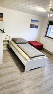 a bedroom with a bed and a red chair at 80qm Monteuroase in Melsungen - Schwarzenberg MwSt ausweisbar in Melsungen