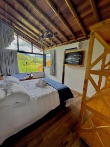 a bedroom with a large bed and a large window at Chalé Choupana - Capim Cidreira in São Bento do Sapucaí