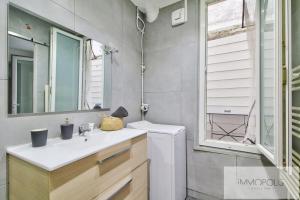 un baño con lavabo y espejo en Bel appartement avec terrasse, en Clichy 5 fotos más
