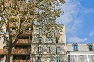 Un edificio alto con un árbol delante. en Bel appartement avec terrasse, en Clichy
