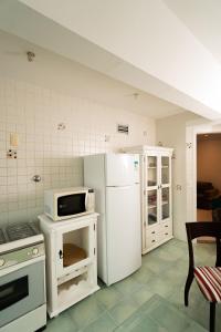 La cuisine est équipée d'un réfrigérateur blanc et d'un four micro-ondes. dans l'établissement Apartamento 100m Praia do Forte, à Cabo Frio