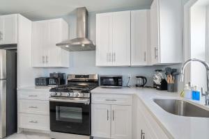 a kitchen with white cabinets and a stove and a sink at 4BR 2BA Luxe Beach Estate II in Atlantic City +31 photos