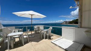a balcony with a table and chairs and an umbrella at Hostel Cantinho do Mar in Salvador