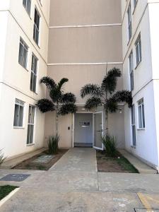 a building with two palm trees in front of it at Apartamento no térreo para 04 pessoas in Vitória da Conquista