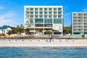 a beach with chairs and umbrellas in front of a hotel at Best Western Premier - The Tides in Orange Beach