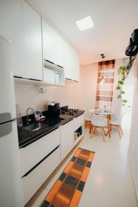 a kitchen with white cabinets and a sink and a table at Conforto e tranquilidade in Vitória da Conquista