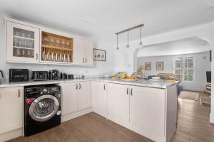 eine Küche mit weißen Schränken und einer Waschmaschine und einem Trockner in der Unterkunft The Postmaster's Retreat in Mickleton