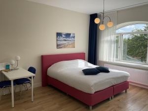 ein Schlafzimmer mit einem Bett, einem Schreibtisch und einem Fenster in der Unterkunft Aristoteles Apartments in Scheveningen