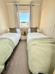 two beds in a room with a window at Miarlo Lodge Derwent Haven Lakeland in Grange Over Sands
