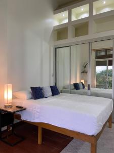 Ciudad Cariariにあるvilla country club cariariのランプ付きの客室内の大きな白いベッド