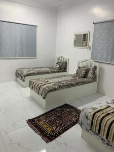 2 Betten in einem weißen Zimmer mit einem Teppich in der Unterkunft Welcome Nine 5km far from Masjid Nabawi in Medina