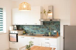 a kitchen with white cabinets and green tile on the wall at Almond b&b in Madonna della Pace