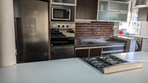 a kitchen with stainless steel appliances and a brick wall at Mishki Wasi - Dulce Hogar Magdalena in Magdalena