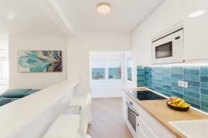 a white kitchen with blue tile on the wall at La Cala Mijas Esmeralda Stunning Sea Views close to the Beach in La Cala de Mijas