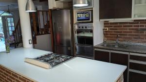 a kitchen with a counter with a stove and a refrigerator at Mishki Wasi - Dulce Hogar Magdalena in Magdalena