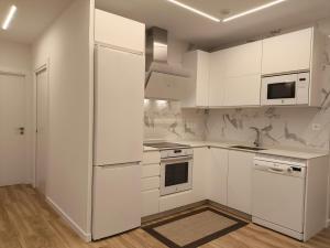 a white kitchen with white cabinets and a refrigerator at Rest Pedrouzo in O Pedrouzo