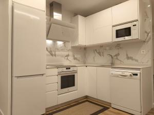 a white kitchen with white cabinets and appliances at Rest Pedrouzo in O Pedrouzo