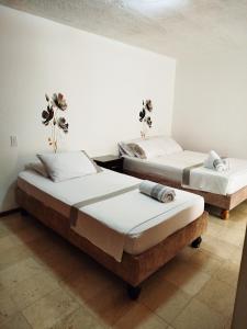 two beds in a room with white walls at Casa San Joaquin in Cali