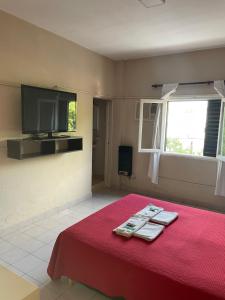 a room with a red bed with a tv on the wall at Hotel Bonino in Villa Mercedes