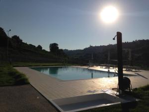 a large swimming pool with the sun in the sky at Cumana Blu Apartments in Campofilone