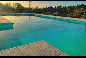 a large swimming pool with blue water at Aldea La Abundancia Cabaña Hostel in La Falda +3 photos