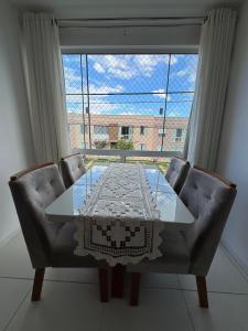 a dining room table with two chairs and a large window at Casa Arruda Climatizado Próx à Shopping Boulevard in Vitória da Conquista