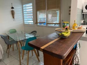 a kitchen with a wooden counter with a glass table at Le PLAYA LODGE maison 2 chambres in Saint-François