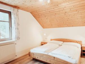 a bed in a room with a wooden ceiling at Alpenquartier Montafon in Tschagguns