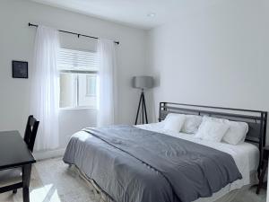a white bedroom with a bed and a window at Modern Family Haven - Minutes from Disney Magic-OC in Midway City