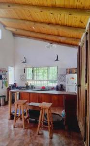eine Küche mit Holzdecken, einem Tisch und 2 Hockern in der Unterkunft La candelaria in Villa Ciudad Parque