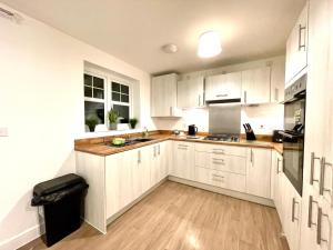 a kitchen with white cabinets and wooden floors at Churchill House 3 Bedroom Sleeps 6 Free Parking in Down Hatherley