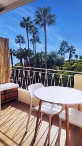 un balcon avec une table, des chaises et des palmiers dans l'établissement La Dolce Vita de Cannes: Luxury city center apartement, beautiful View, à Cannes