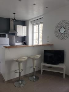 a kitchen with a bar with stools and a tv at Saint-Chéron - superbe appartement lumineux in Saint-Chéron
