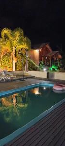 a swimming pool in front of a house at night at Pousada chalés Sobre as Nuvens in Barracão