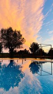 einen Pool aus Wasser mit einem Baum und einem wolkigen Himmel in der Unterkunft Olive Villa in Alcantarilha