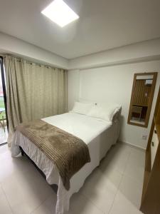 a bedroom with a large white bed with a window at Makani Flat Campas in Tamandaré +18 photos