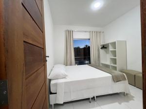 ein Schlafzimmer mit einem weißen Bett und einem Fenster in der Unterkunft Casa céu de estrelas in Arraial d'Ajuda