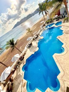 a pool on the beach with chairs and the ocean at Espectacular Apto a pie de Playa con vista al mar in Manzanillo