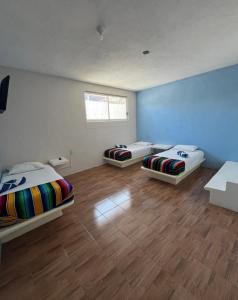 trois lits dans une chambre avec parquet dans l'établissement La Casa De La Abuela, à Zihuatanejo 2 autres photos