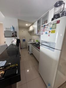 a kitchen with a white refrigerator with magnets on it at Apartamento Ondina Salvador in Salvador