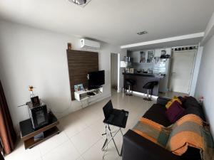 a living room with a black couch and a kitchen at Apartamento Ondina Salvador in Salvador