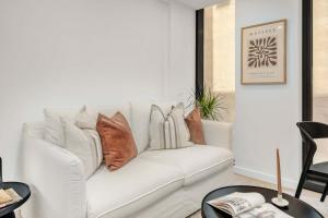 a living room with a white couch with pillows on it at Perfectly Paired - Your Dual Apartment Escape in Wellington