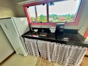 Una cocina con encimera con fregadero y ventana. en Cara,Viva Flats, en Porto Seguro