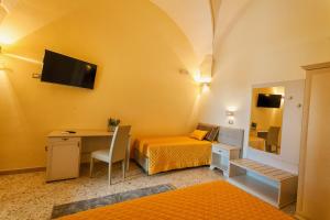 a small room with a bed and a desk and a television at Le Radici in Uggiano la Chiesa