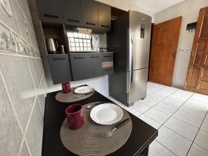 a kitchen with a black counter and a refrigerator at Sobrado do Aconchego - Jardim Carvalho in Ponta Grossa