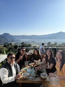 a group of people sitting around a wooden table at บ้านชมหมอก ภูลังกา in Ban Sakoen +16 photos
