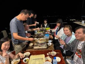 a group of people sitting around a table eating food at บ้านชมหมอก ภูลังกา in Ban Sakoen