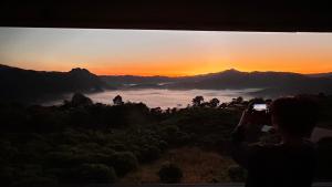a person taking a picture of the sunset at บ้านชมหมอก ภูลังกา in Ban Sakoen