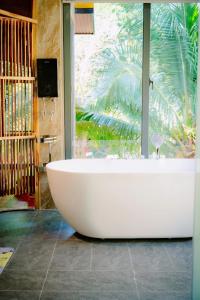 a large white bath tub in a room with a window at Khu du lịch Suối Ong in Buôn Erang