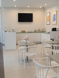 Un comedor con mesas y un televisor en la pared. en Residenza Sansevero - Dimore Partenopee, en Nápoles